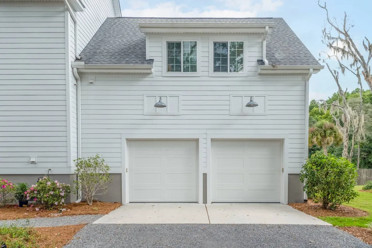 This image features the home's garage doors, upper windows, and landscaped garden area. It highlights the well-maintained exterior and the garden's inviting space for outdoor gatherings, aligning with the idea of connecting with nature and community.
