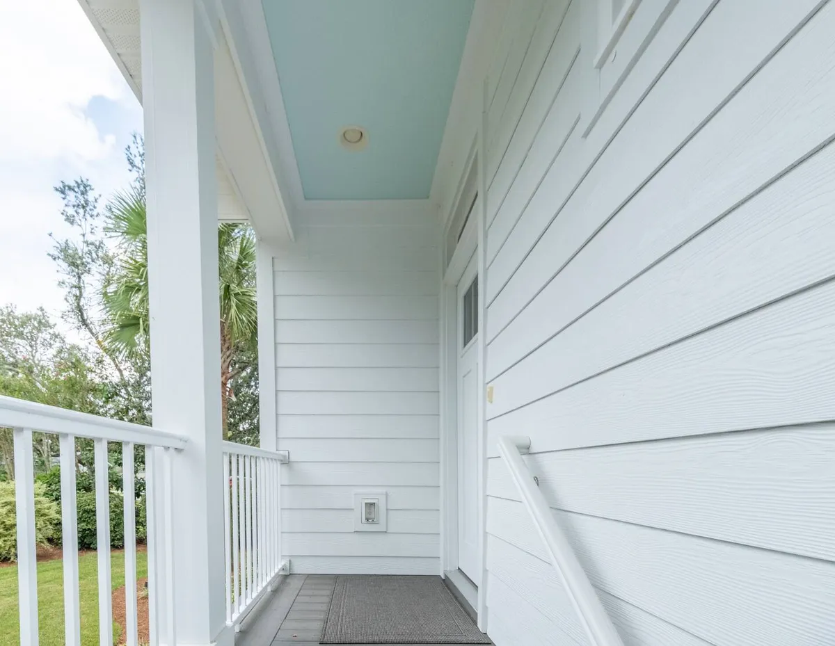 A serene, light-filled entry space with white siding, a blue ceiling, and a sturdy railing. The area suggests a transition zone, ideal for morning rituals and peaceful starts to the day.